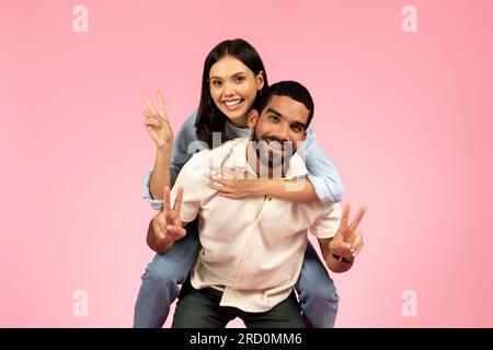 Happy cute loving couple having fun on pink background Stock Photo