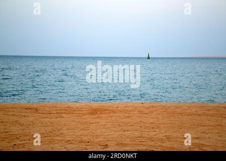 Three stripes in the form of blue sky, blue sea and yellow sand. Buoy on the horizon. Stock Photo