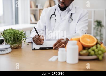 Expert in nutrition making special menu for patient and writing list of allowed products on clipboard paper during work time in hospital. Stock Photo