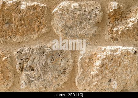 Old beige stone wall background texture close up. Castle wall surface, antique natural stonewall Stock Photo