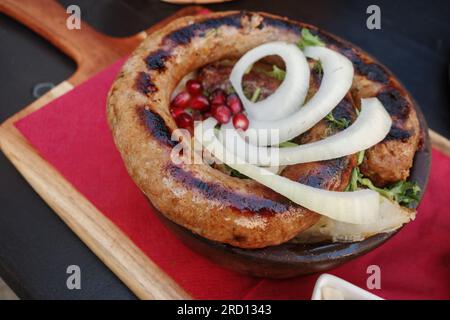 Top view, curl of Kupati,  Georgian spicy sausage with distinct flavor, on top with onion and barberry. Stock Photo