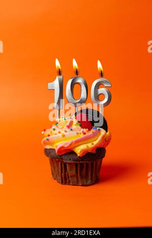 birthday cake with number 106 - cupcake on orange background with birthday candles Stock Photo