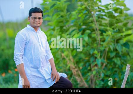 Portrait of happy young indian farmer couple touching wheat crop ...