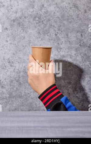 take away coffee cup in human hand on grey background, selective focus Stock Photo