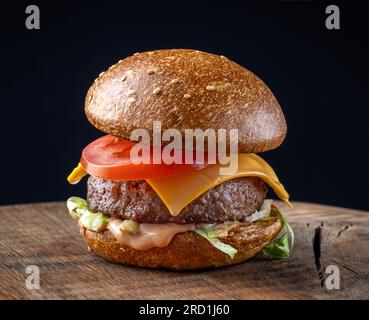 fresh tasty burger on wooden board and black background Stock Photo