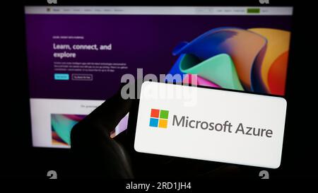 Person holding smartphone with logo of cloud computing platform Microsoft Azure on screen in front of website. Focus on phone display. Stock Photo