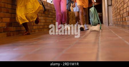 Low section of diverse schoolgirls with bags walking in elementary school corridor Stock Photo