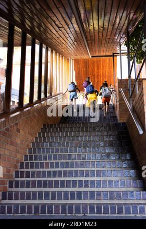 Diverse schoolgirls with bags running in elementary school staircase Stock Photo