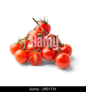 Heap of ripe fresh cherry tomatoes on green branches isolated on white background. Stock Photo