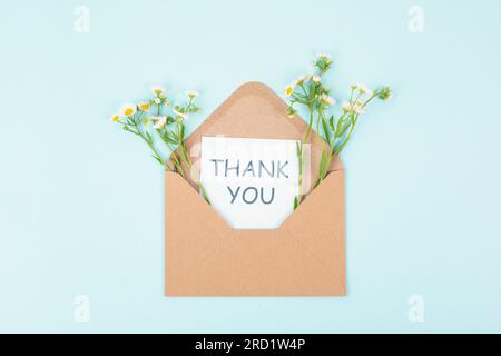 Thank you card in an envelope surrounded by flowers, being thankful, support, help and charity concept, positive attitude Stock Photo