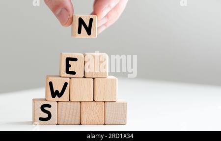 2023 News new year symbol. Businessman turns a wooden cube and changes words News 2022 to News 2023. Beautiful grey table grey background, copy space Stock Photo