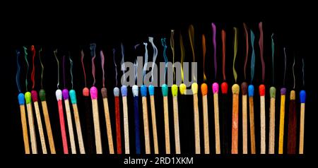 matchsticks of various shapes and colors with smoke on black background Stock Photo