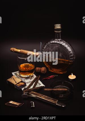 Quality cigars with cognac, cutter, 100 dollar paper, ashtray, light candle, photo film and red hot pepper on black background Stock Photo