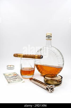Quality cigars with cognac, cutter, 100 dollar paper, light candle and ashtray on white background Stock Photo