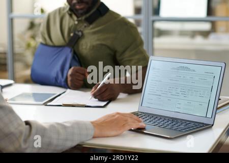 Close-up of businesswoman typing document on laptop while having meeting with client in office Stock Photo