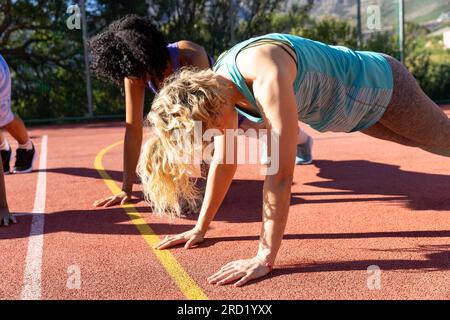 Diverse group of women doing push ups and warming up at basketball court Stock Photo