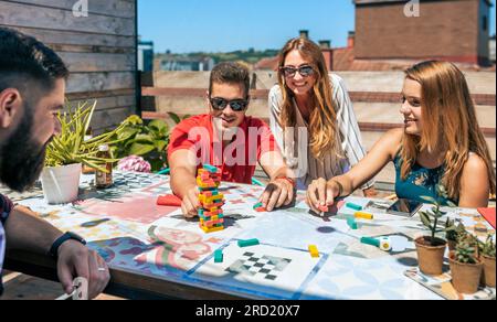 Group of happy office workers playing with jenga game on terrace in a coffee break Stock Photo