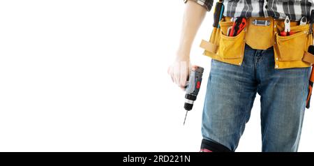 Man wearing mounting belt with tools for repair holding drill in hands isolated on white background. Professional equipment of handyman Stock Photo