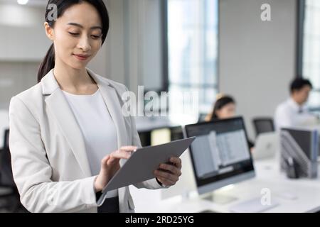 Successful Chinese businesswoman using digital tablet in office Stock Photo