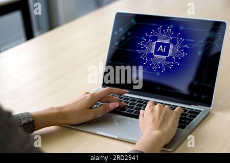 Business woman is entering data on her laptop computer, which prominently exhibits the AI logo, symbolizing her engagement in creative digital work. Stock Photo