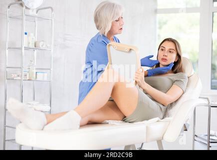 Young patient looking in mirror at clinic. Stock Photo