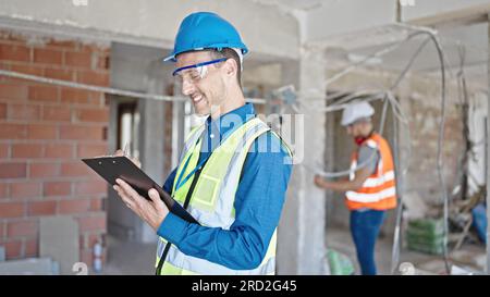 Two men builders writing document working at construction site Stock Photo