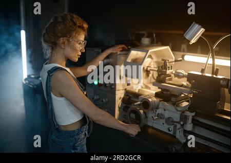 Young blond woman mechanical engineer working on lathe machine Stock Photo