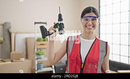 Young beautiful hispanic woman builder smiling confident holding drill at street Stock Photo