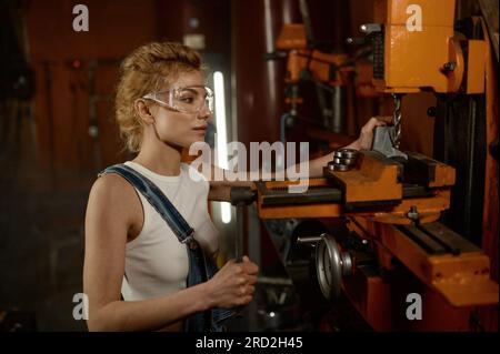 Woman wearing safety protective goggles working on milling and drilling machine Stock Photo