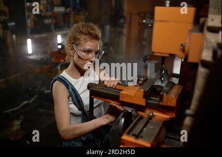 Woman wearing safety protective goggles working on milling and drilling machine Stock Photo