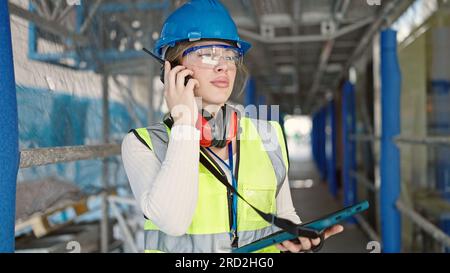 Young blonde woman architect talking on walkie-talkie using touchpad at street Stock Photo