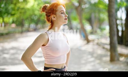 Young redhead woman wearing sportswear breathing at park Stock Photo