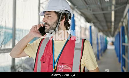 Young hispanic man builder talking on smartphone standing at street Stock Photo