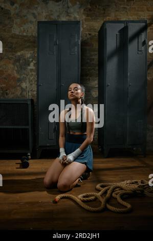 Beautiful woman boxer relaxing meditating sitting on floor in gym Stock Photo