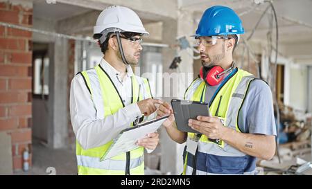 Two men builders and architect using touchpad shake hands at construction site Stock Photo