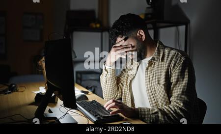 Young hispanic man business worker using computer stressed at office Stock Photo