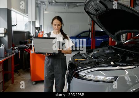 Back view on woman auto engineer doing computer diagnostic Stock Photo