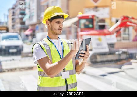 Young hispanic man architect drawing on touchpad at park Stock Photo