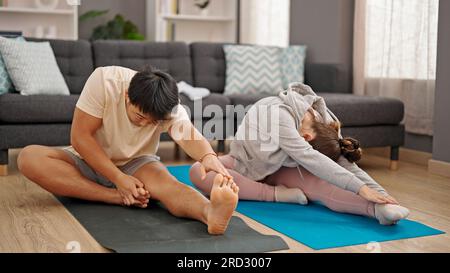 Man and woman couple sitting on floor doing yoga exercise at home Stock Photo