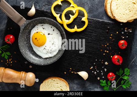 Fried eggs in a frying pan with fresh vegetables and spices. Concept for menu and advertising. Stock Photo