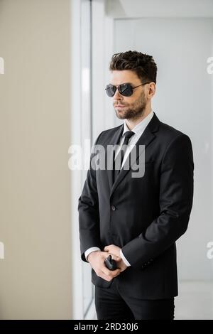 https://l450v.alamy.com/450v/2rd30j6/surveillance-bodyguard-standing-with-walkie-talkie-man-in-sunglasses-and-black-suit-with-tie-hotel-safety-security-management-uniformed-guard-on-2rd30j6.jpg