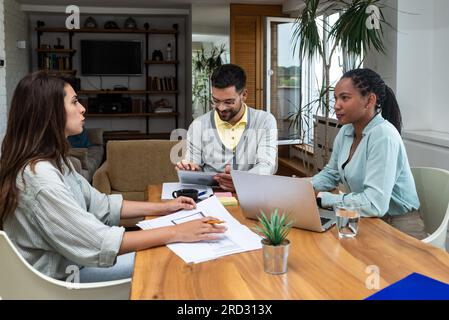 Young designer giving some new ideas about project to his partners in conference room. Businesspeople discussing over new business project in office. Stock Photo