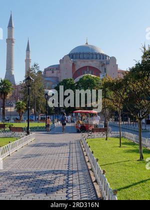 Gardens of Sultanahmet Park with the Hagia Sophia Mosque. Red vending cart sells roasted corn. Istanbul, Turkey Stock Photo