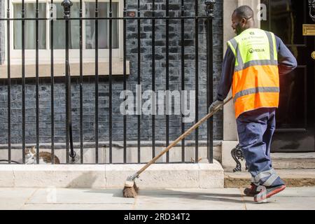 Downing Street, London, UK. 18th July 2023.  A Veolia cleaner for the City of Westminster sweeps outside number 10 Downing Street under the watchful eye of Larry he Cat. Photo by Amanda Rose/Alamy Live News Stock Photo