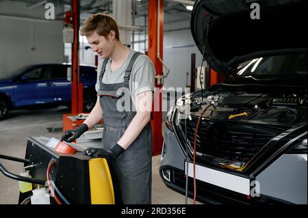 Man auto mechanic entering data for refilling of car air conditioner Stock Photo