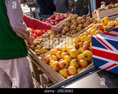 BRITISH APPLES MARKET UNION JACK FLAG BOX Buying UK browsing choosing British English produce apples at an outdoor British Farmers Market stall UK Stock Photo