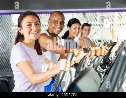 People having running elliptical trainer class in club Stock Photo