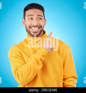 Asian man, smile and hand pointing to studio for news, deal and discount or how to guide on blue background. Happy, choice and male show timeline Stock Photo