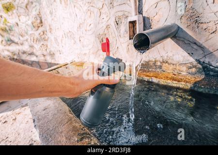 Pouring water from a spring source at camping or hiking. Clean looking water can be contaminated and dangerous to health Stock Photo