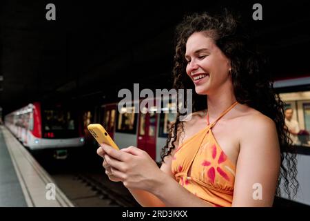 beautiful young woman waiting subway and using smartphone Stock Photo